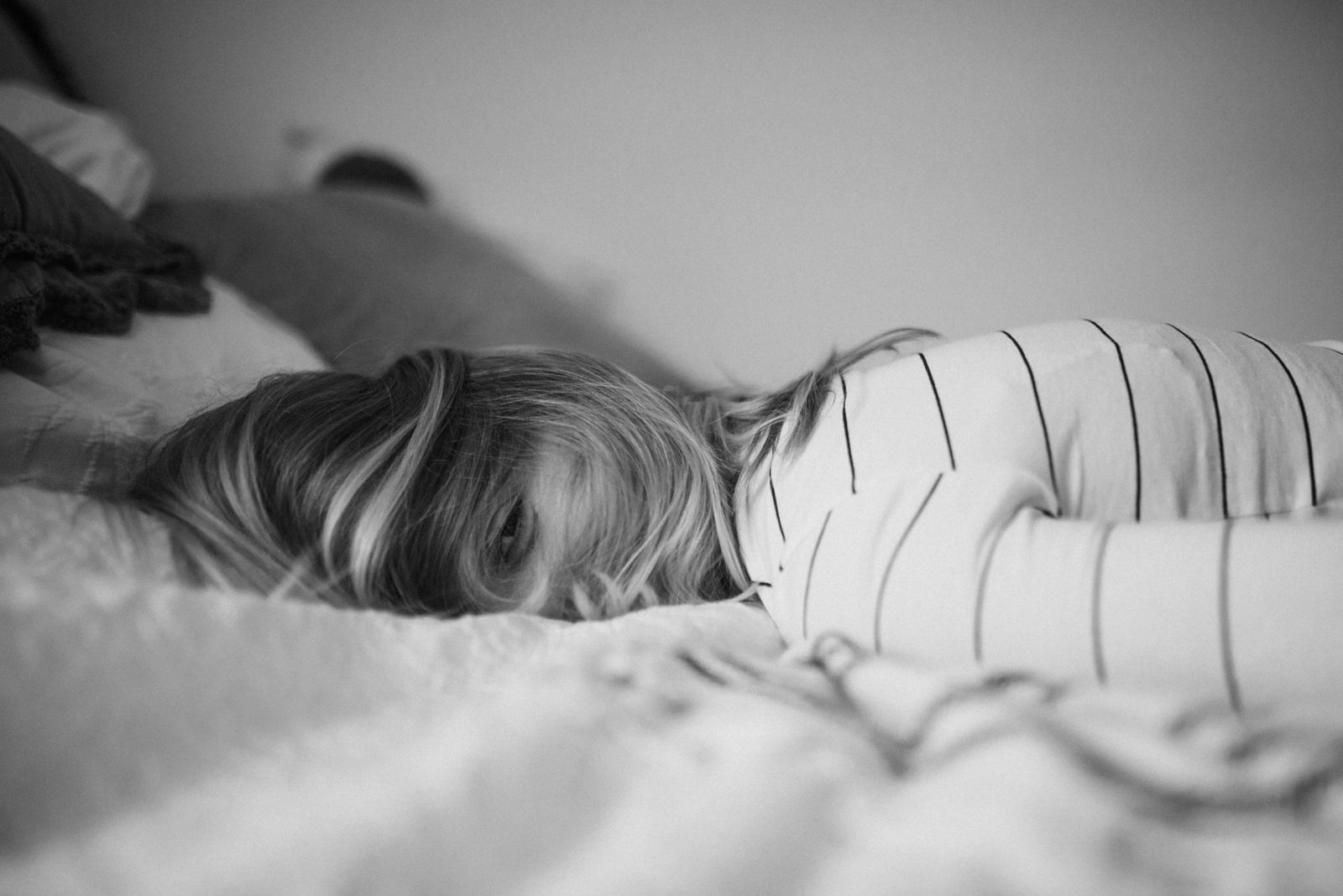 Mamá recostada en la cama, cubriéndose la cara con el cabello